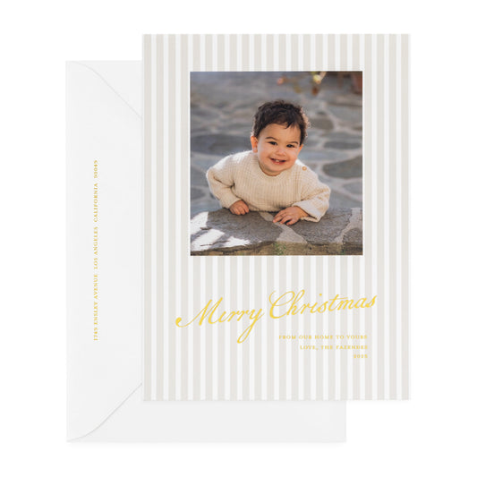 Beige stripe oversized custom holiday card with gold foil 'merry christmas from our home to yours' with photo of little boy paired with a white envelope with gold foil return address