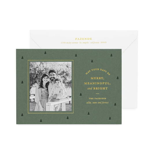 Pine green custom holiday photo card paired with a black and white family photo with gold foil greeting 'may your days be merry, meaningful, and bright' with dark green tree pattern letterpress printed paired with a white envelope with gold foil return address
