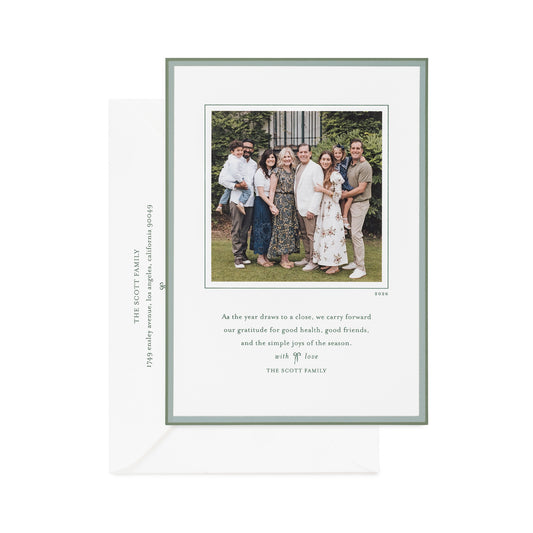 A personalized family holiday photo card with a double green hand-painted border, featuring a custom family photo, a quote, and the name 'The Scott Family' printed in green ink on the card and envelope