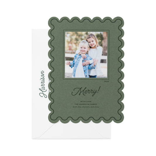 A rosemary green holiday photo card with a scalloped border, featuring a custom family photo of two girls, the text 'Happy Holidays' in script in dark green ink, and the name 'Harrison' printed on the white envelope.
