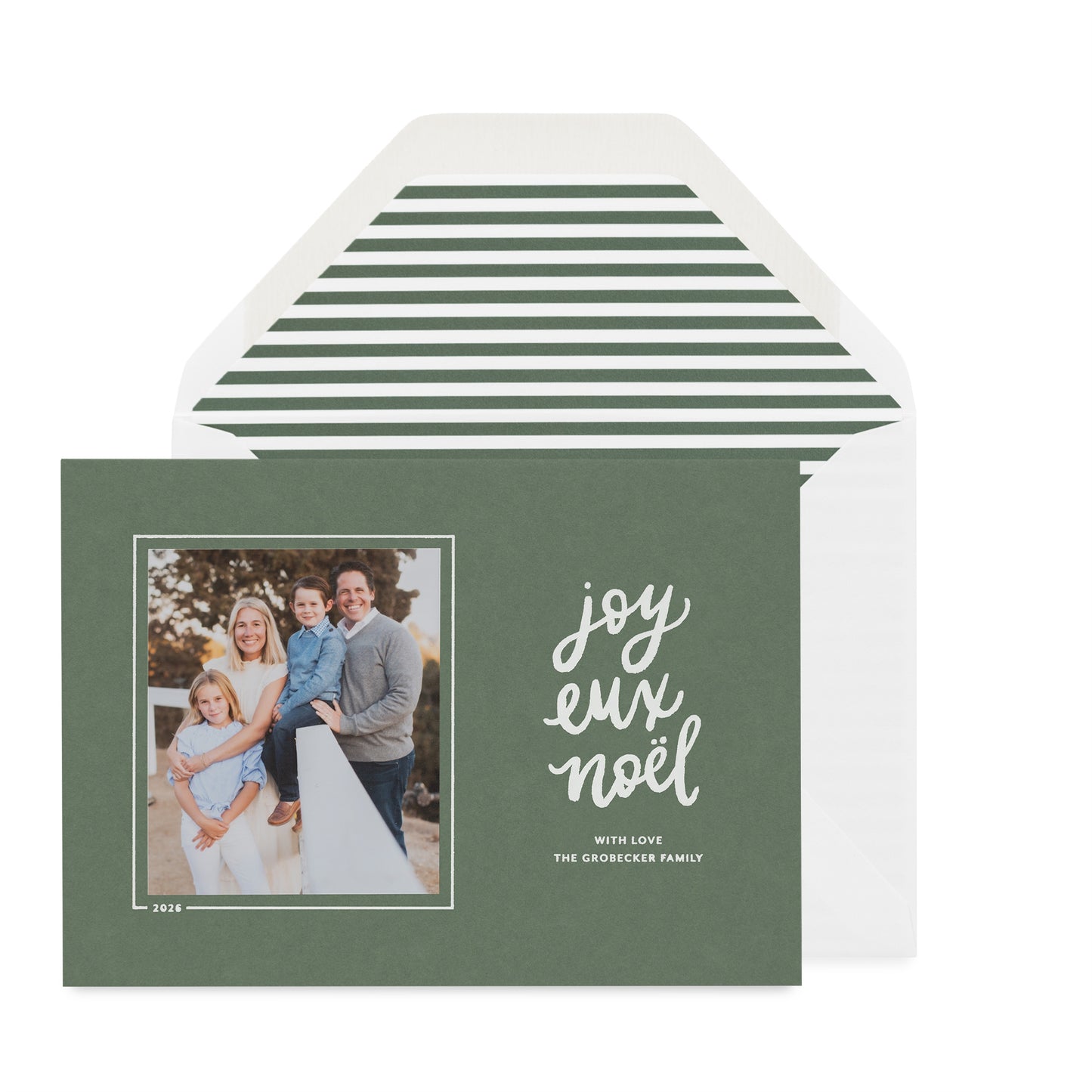 A dark sage green holiday photo card with a white envelope behind it with a green stripe envelope liner featuring a family photo on the left and the words 'joyeux Noel' in white script