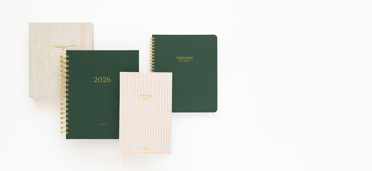 Four planners and guided notebooks of different colors and designs on a white background