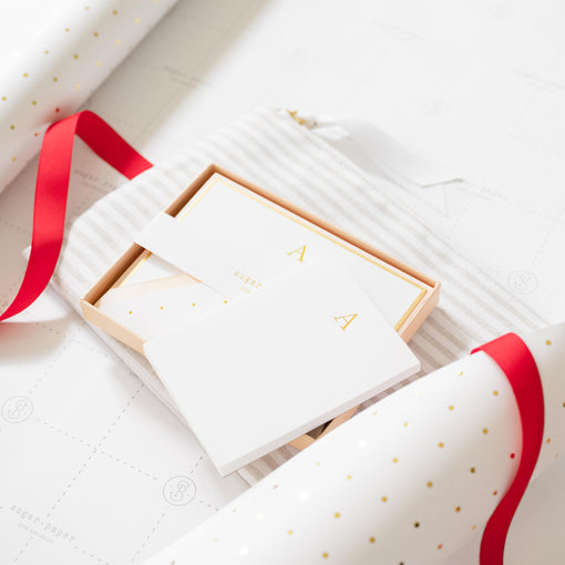Gifts red ribbon on white gift wrap with gold dots.