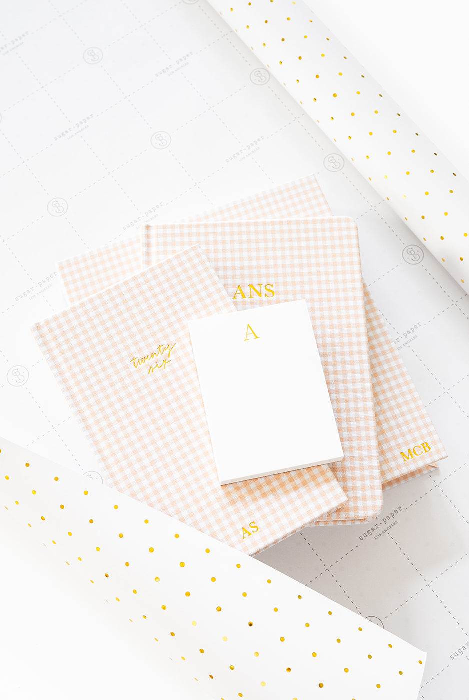 Set of pink checkered books with gold monograms on a white with gold polka dot wrap.
