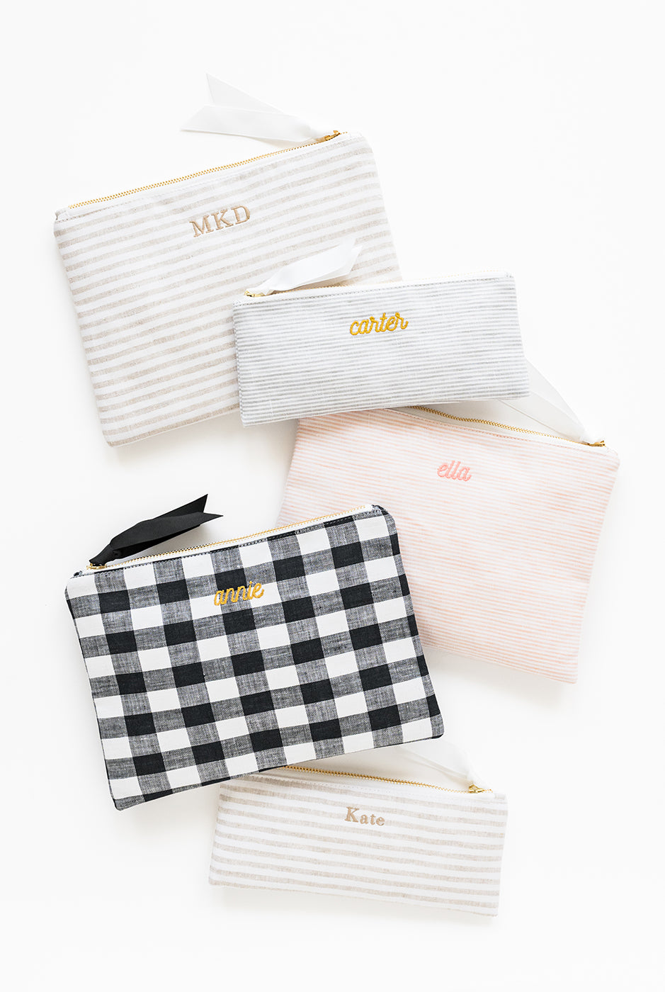 Set of white pouches with personalized names on a white background