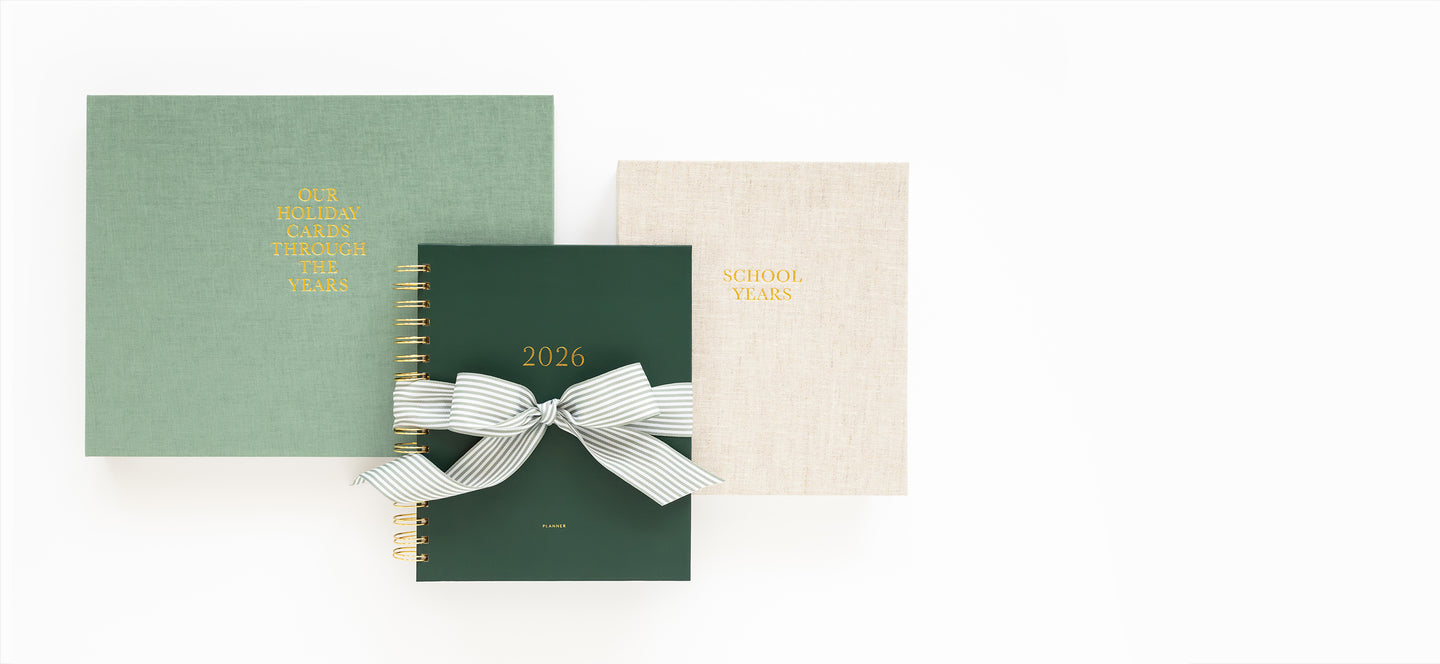 Three books in green, beige, and white with decorative ribbons on a white background