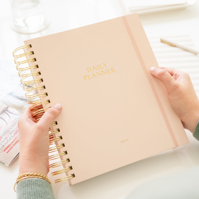 Pale pink daily spiral planner in hands