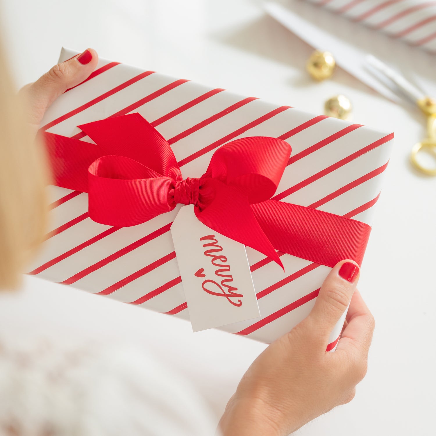 White and red stripe wrapping paper wrapped gift with large red bow and red merry heart gift tag
