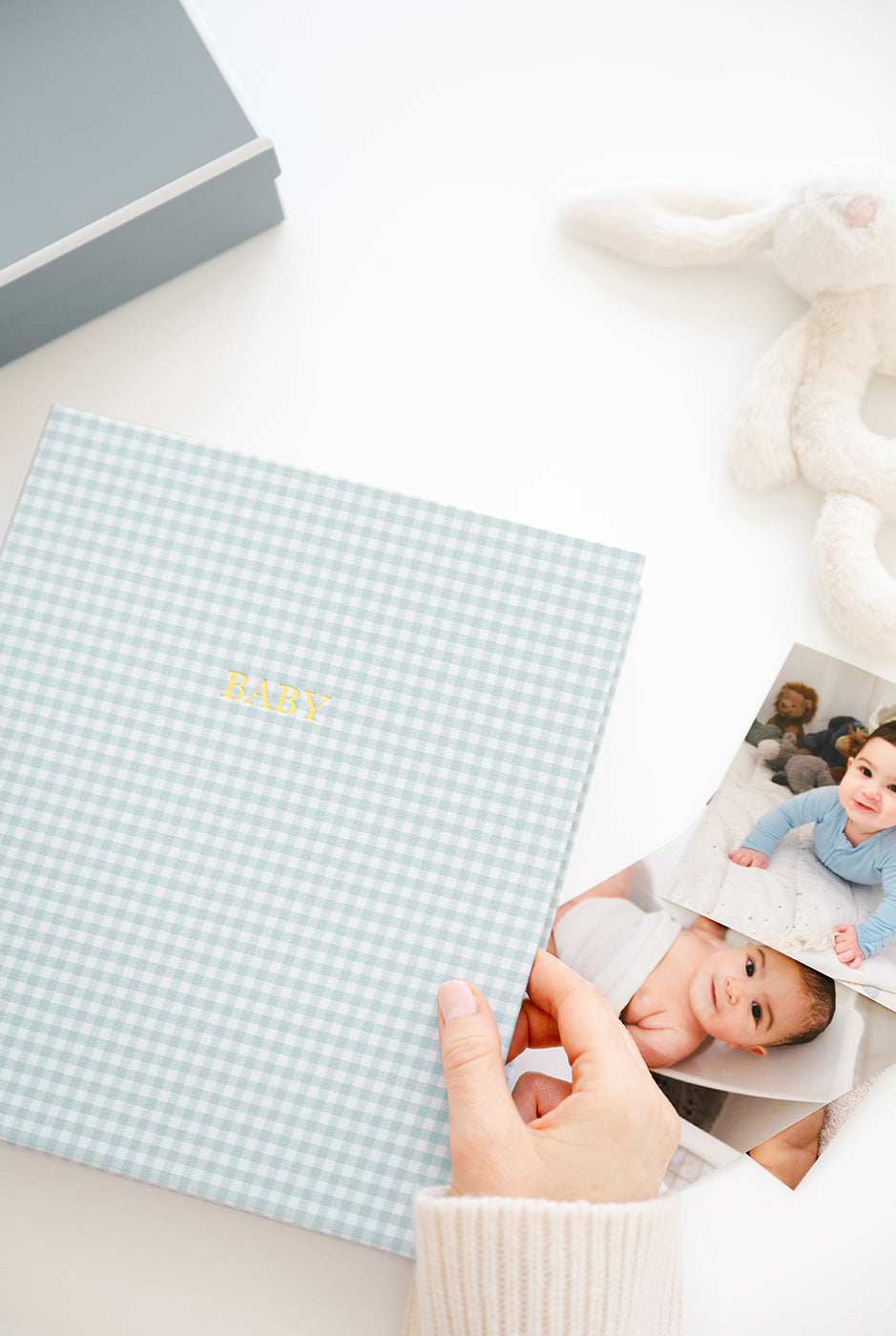 Person holding a baby book with a checkered cover.