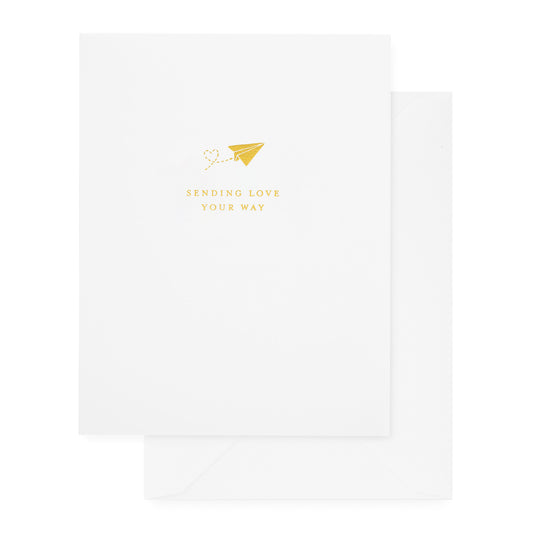 white folded card with gold sending love your way text with paper airplane icon