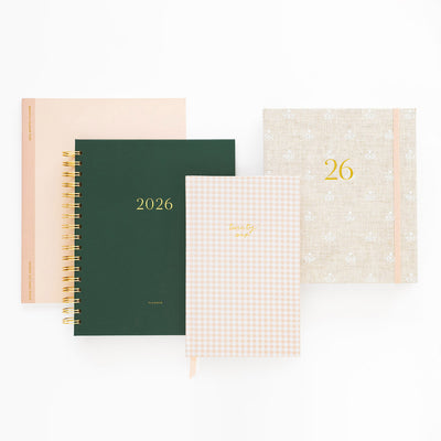 Four different designs of planners with '2026' printed on them, including a green one and a beige one with a grid pattern.