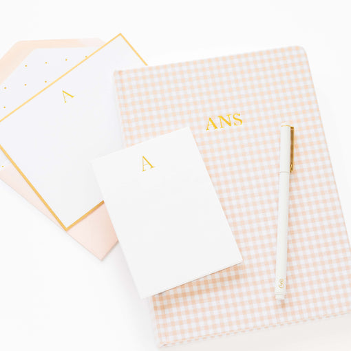 Notebook with gingham pattern and gold monogram on a white background