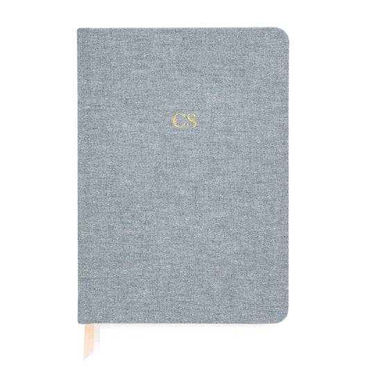A blue fabric journal with a monogram 'CS' embossed on the cover.