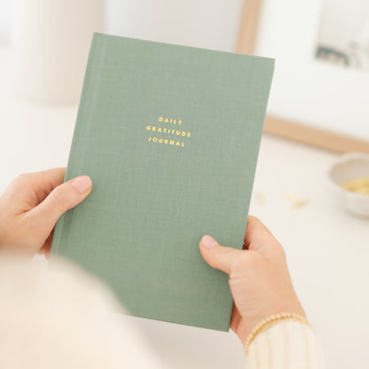 Daily gratitude journal in olive green in hand