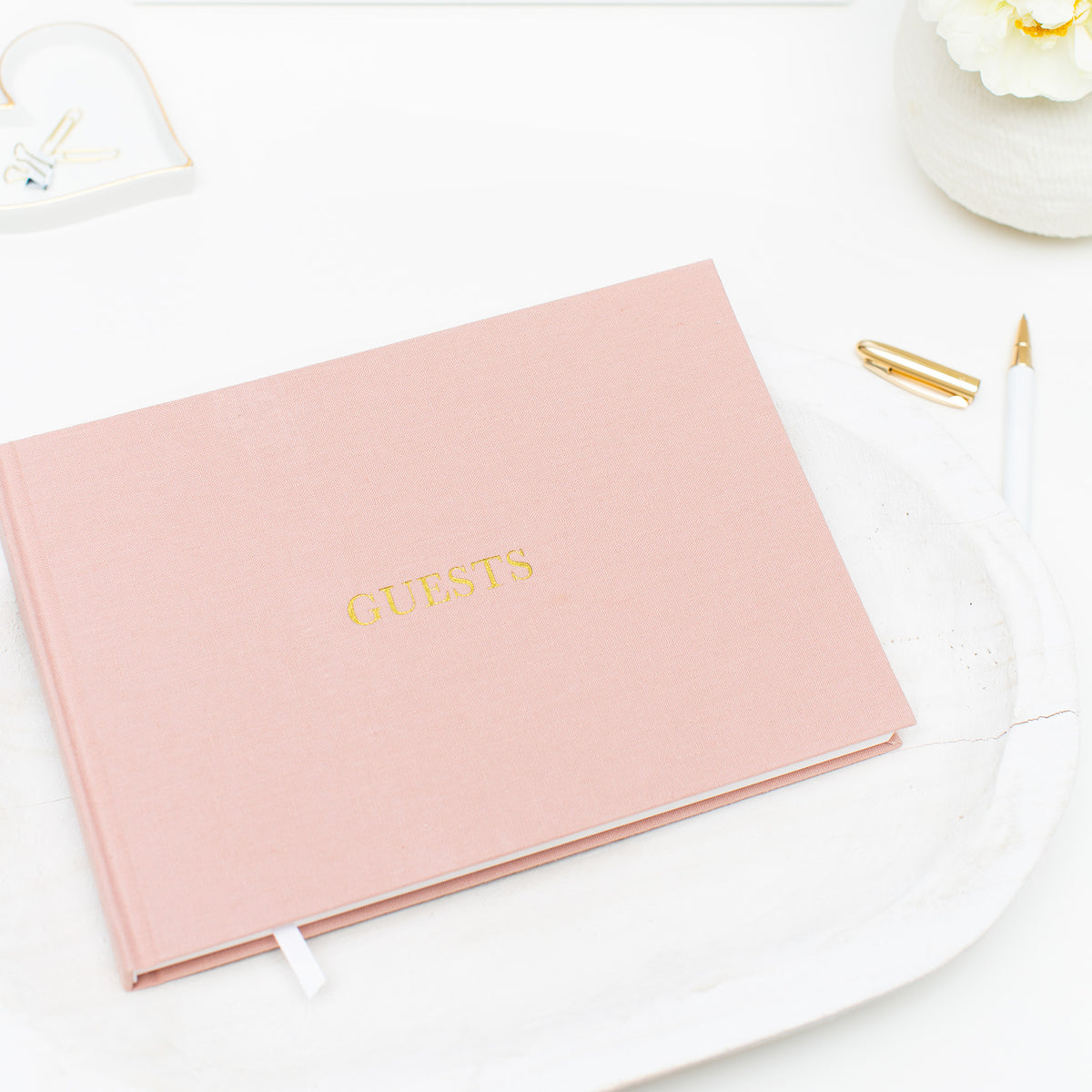 Photo of rose guest book on table with pen