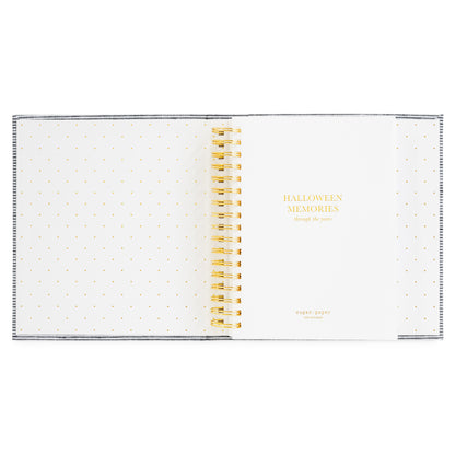 A spiral-bound memory book with white pages with gold polka dots on the pages and gold lettering that reads 'HALLOWEEN MEMORIES through the years' on the cover and gold spiral binding