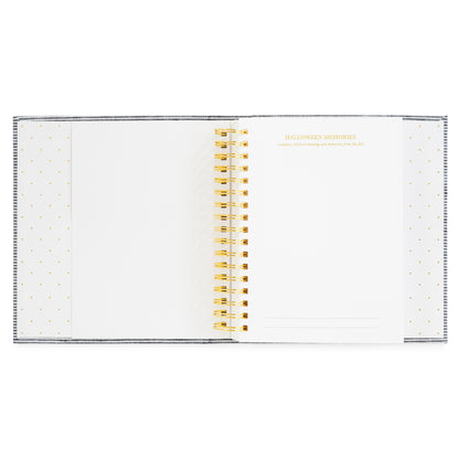 An open spiral-bound keepsake book with white pages, decorated with gold polka dots on the sides and gold text reading 'HALLOWEEN MEMORIES' on the right page. The pages are held together by a gold spiral coil.