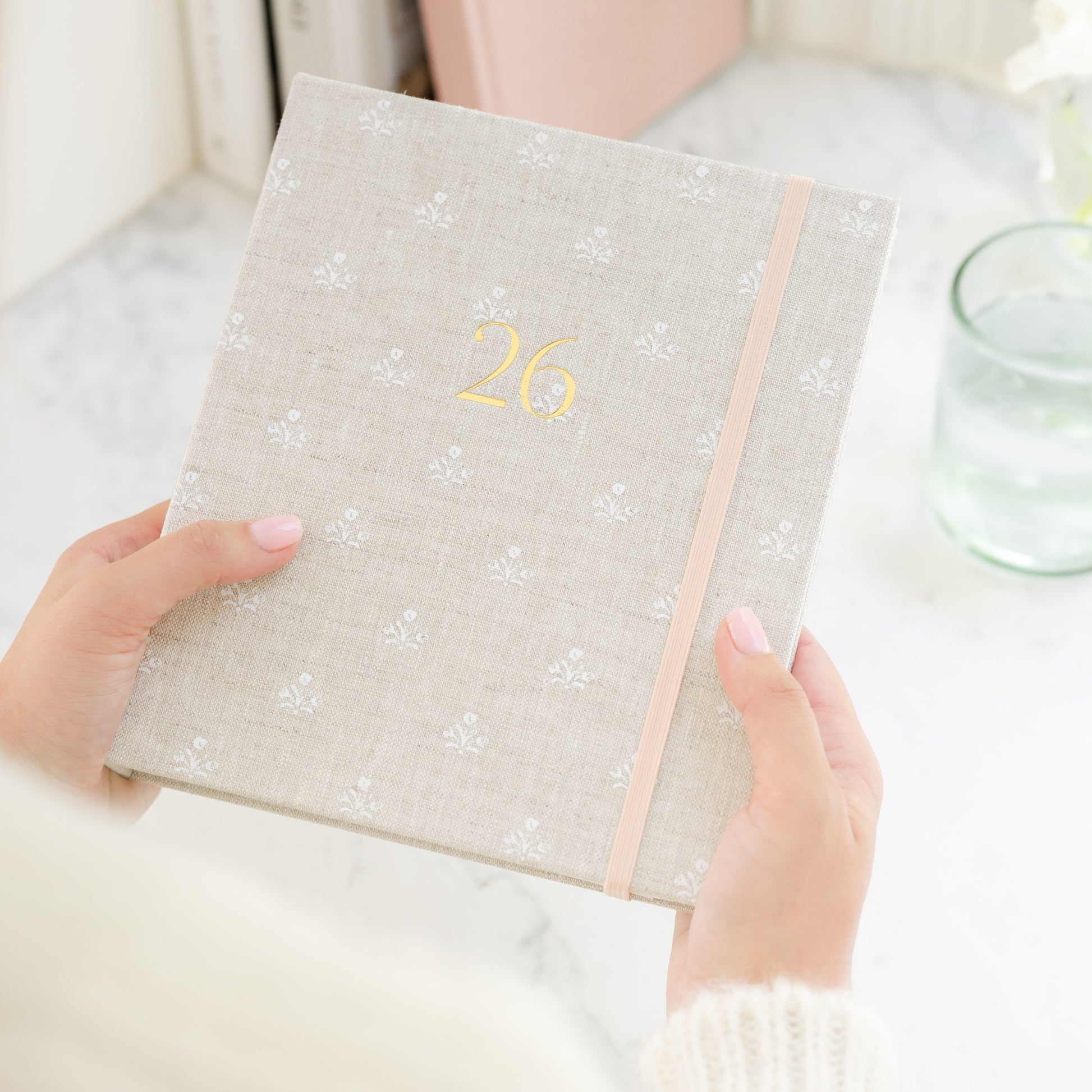Person holding 26 fabric bound concealed planner with beige and white floral fabric cover