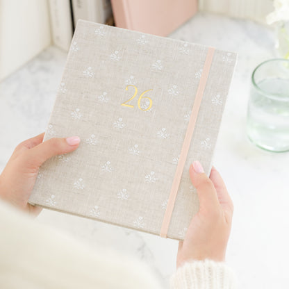 Person holding 26 fabric bound concealed planner with beige and white floral fabric cover