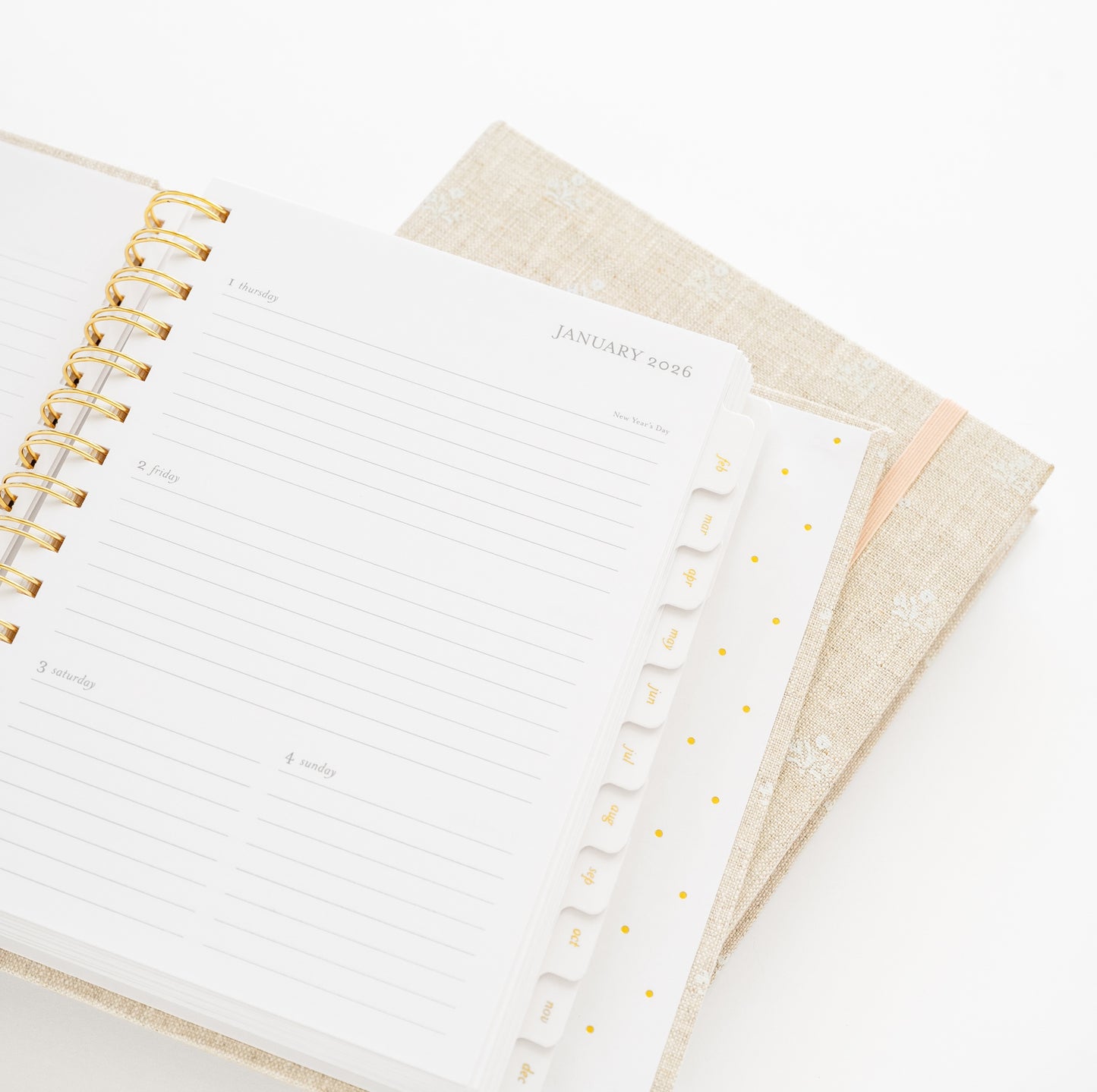 Open planner with gold spiral binding to january 2026 showing tabs for each month