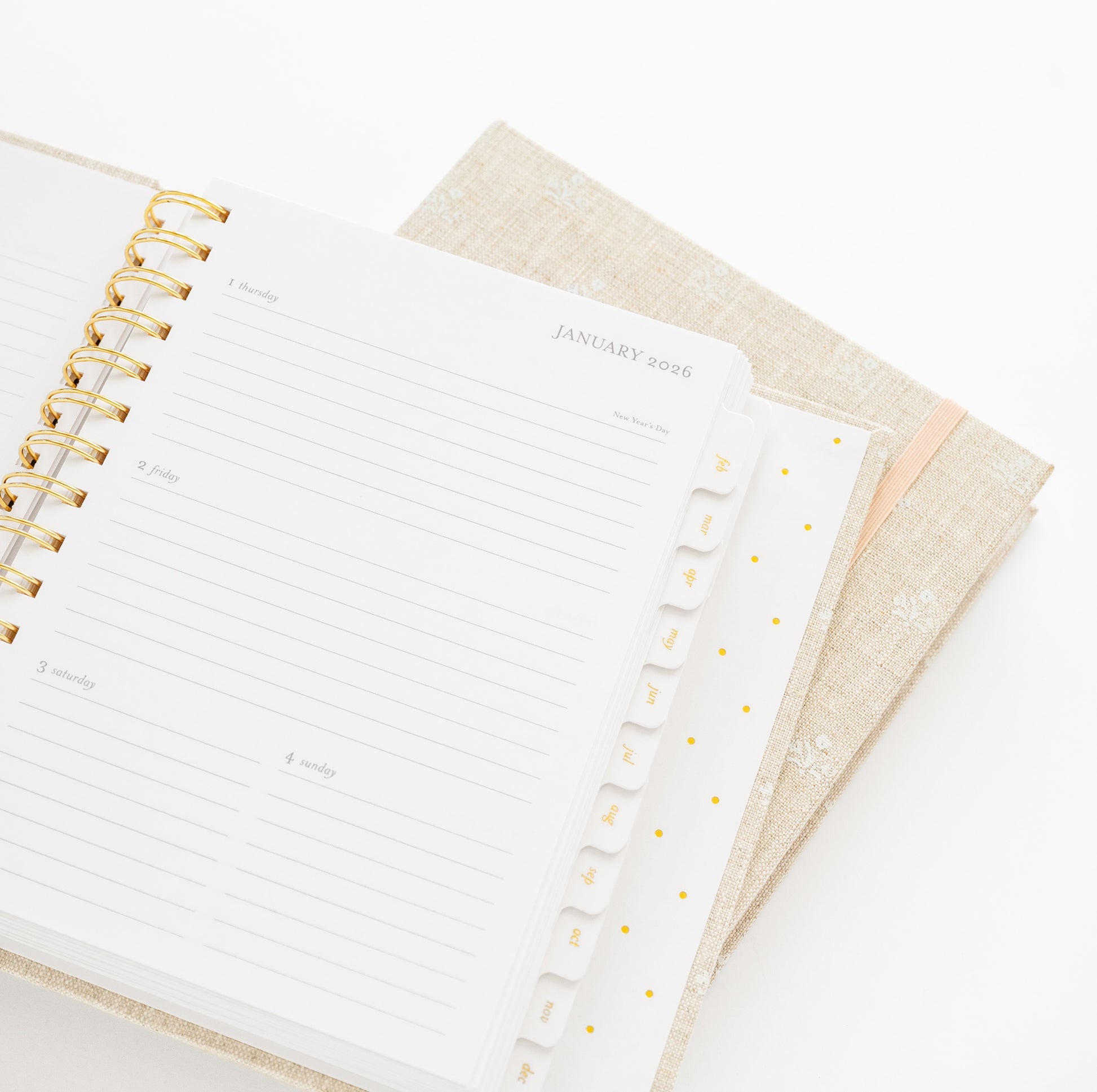 Open planner with gold spiral binding to january 2026 showing tabs for each month
