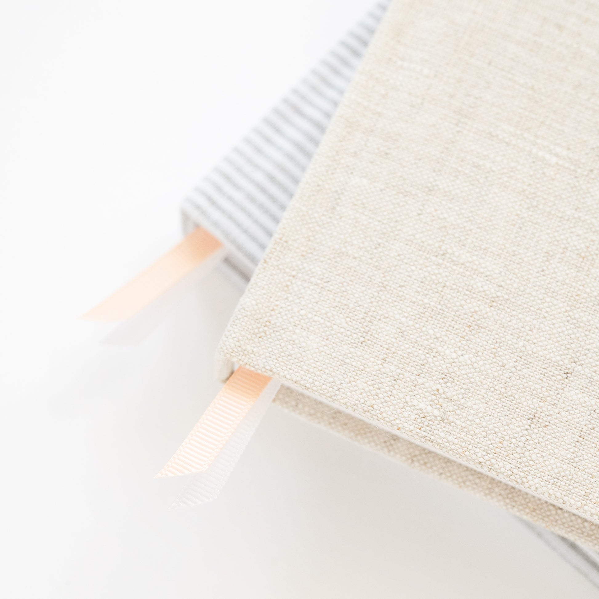 Close-up of a textured beige and grey stripe agenda and the pink and white ribbon markers