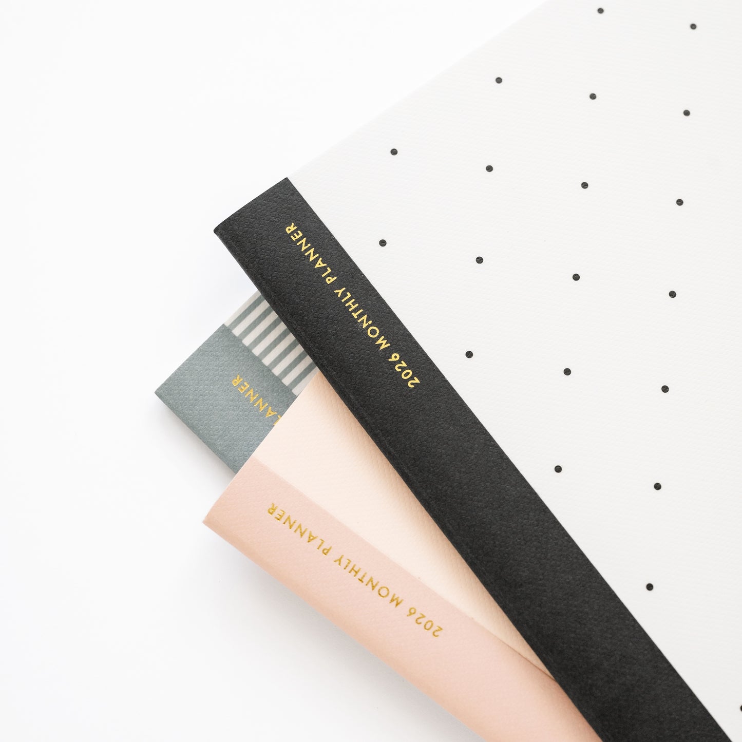 Stack of monthly planners with tape binding in blue, black and pink
