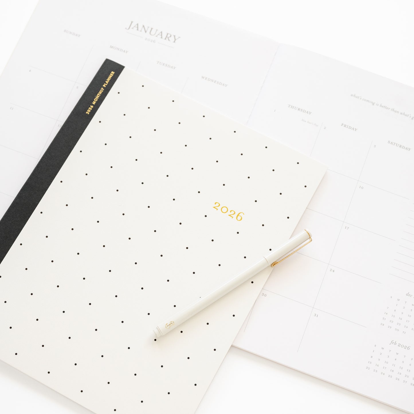 Closeup of cover of 2026 monthly black dot planner cover with open spread of january month