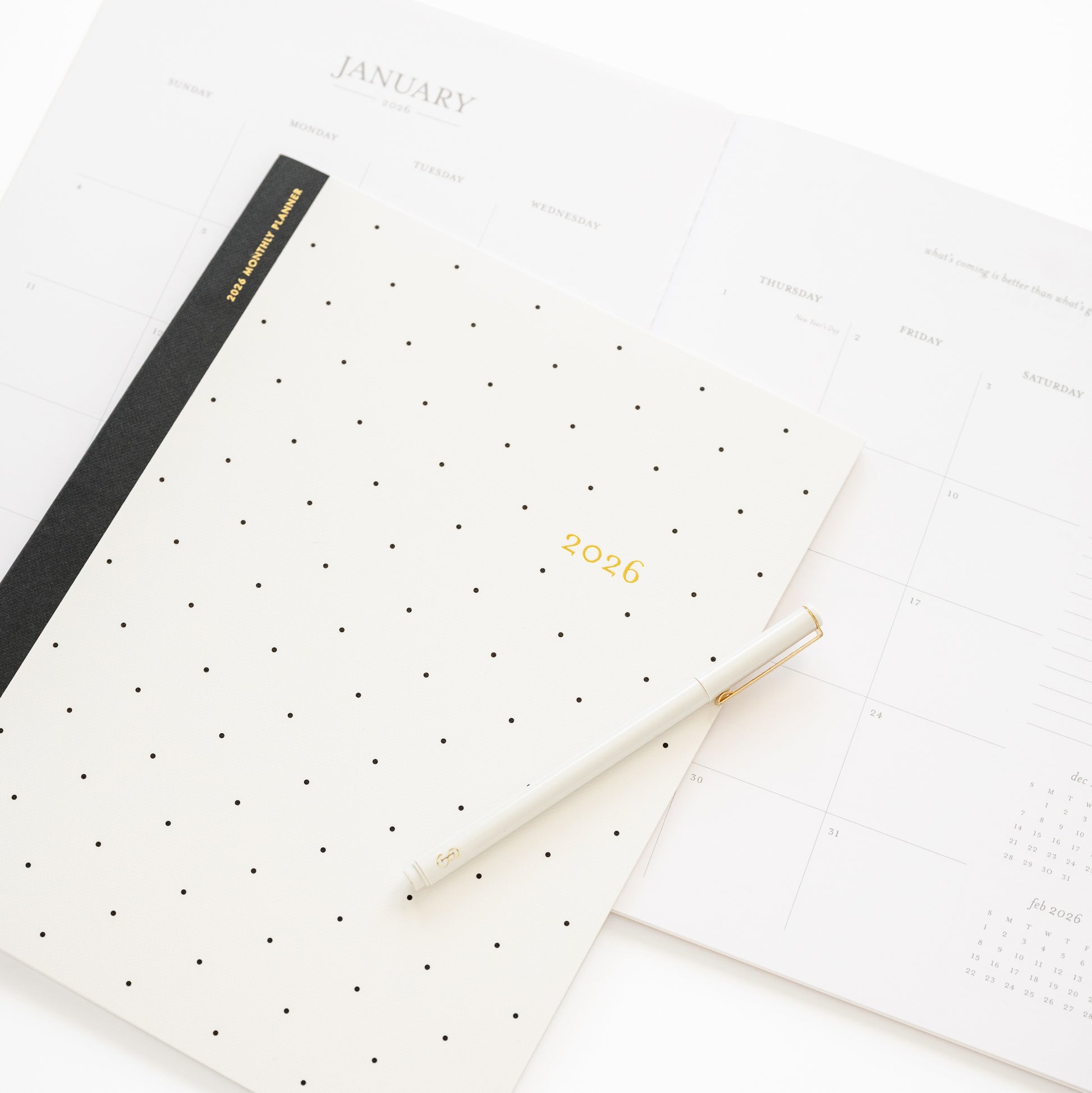 Closeup of cover of 2026 monthly black dot planner cover with open spread of january month