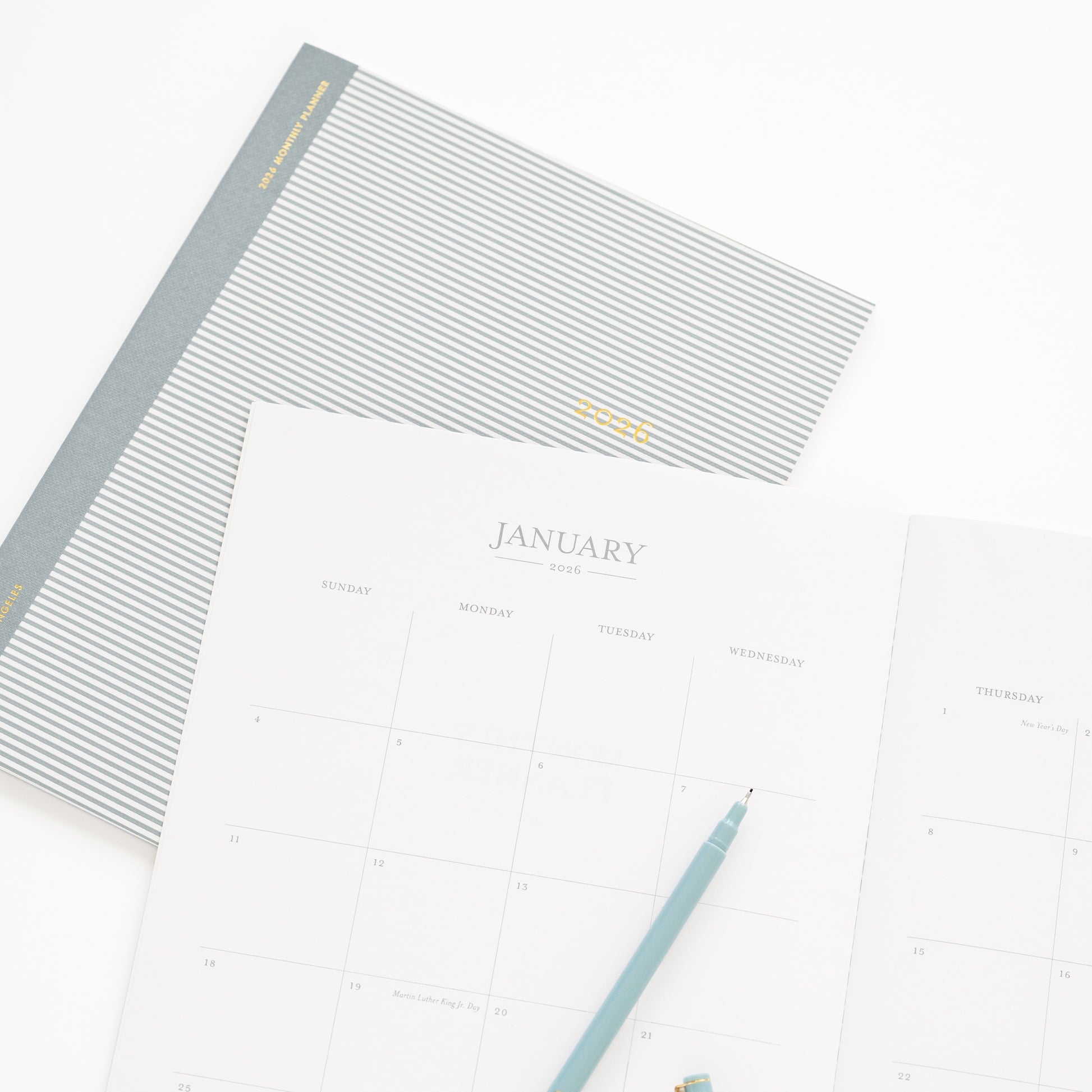 Blue stripe monthly 2026 planner with cover and open to monthly grid for january