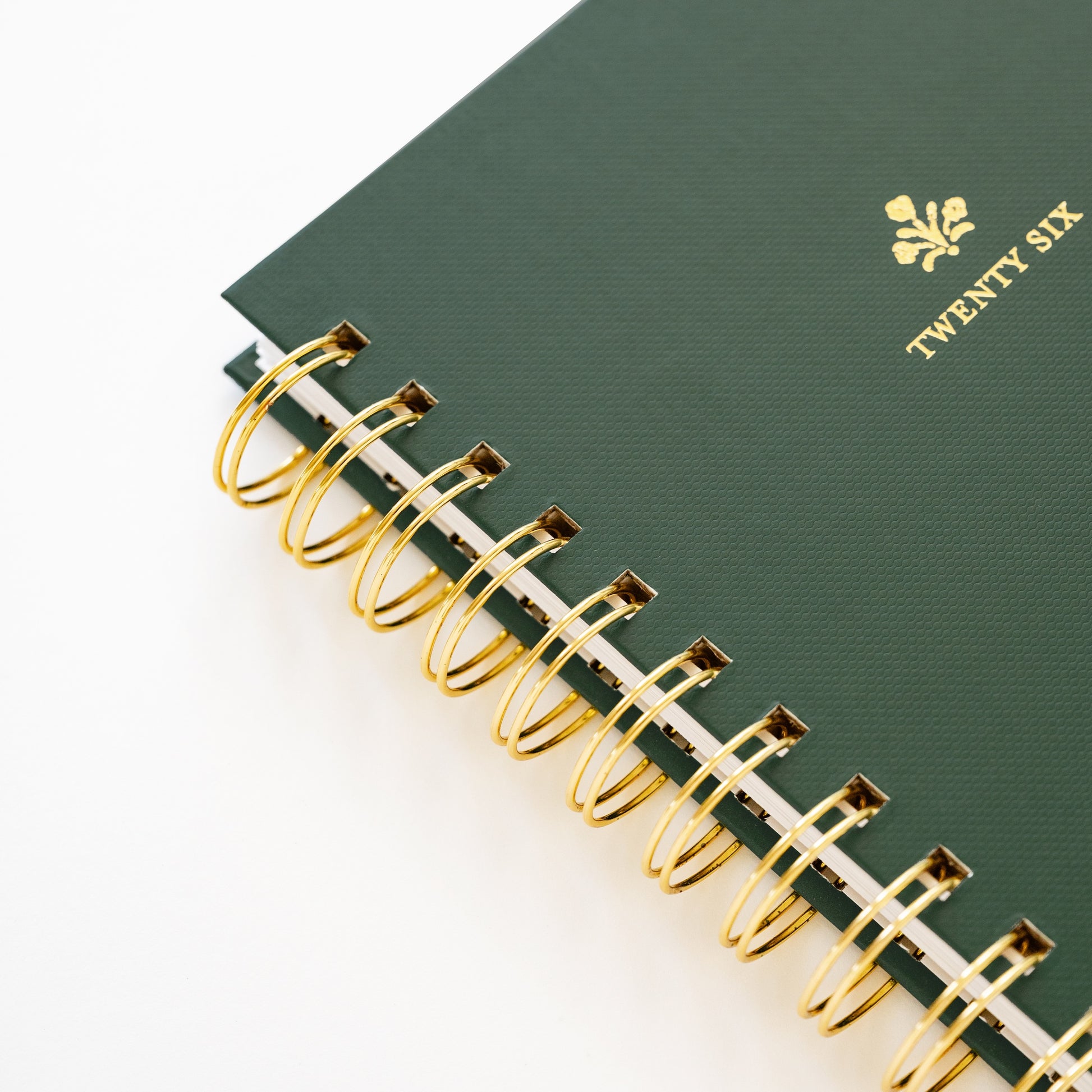 Close up of small green spiral planner with 'twenty six' in gold foil on cover and gold spiral binding