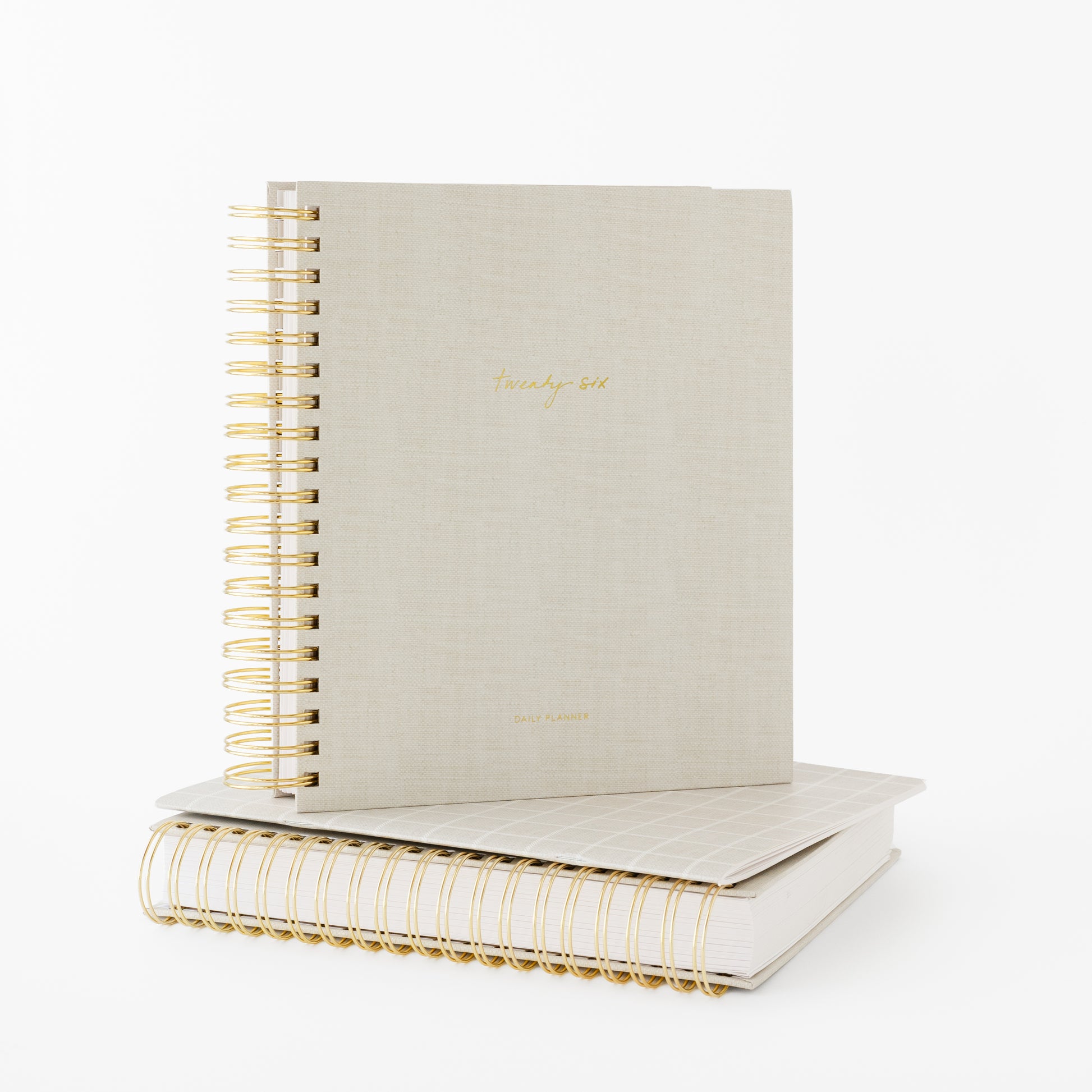 Two beige spiral planners with gold wire binding stackced