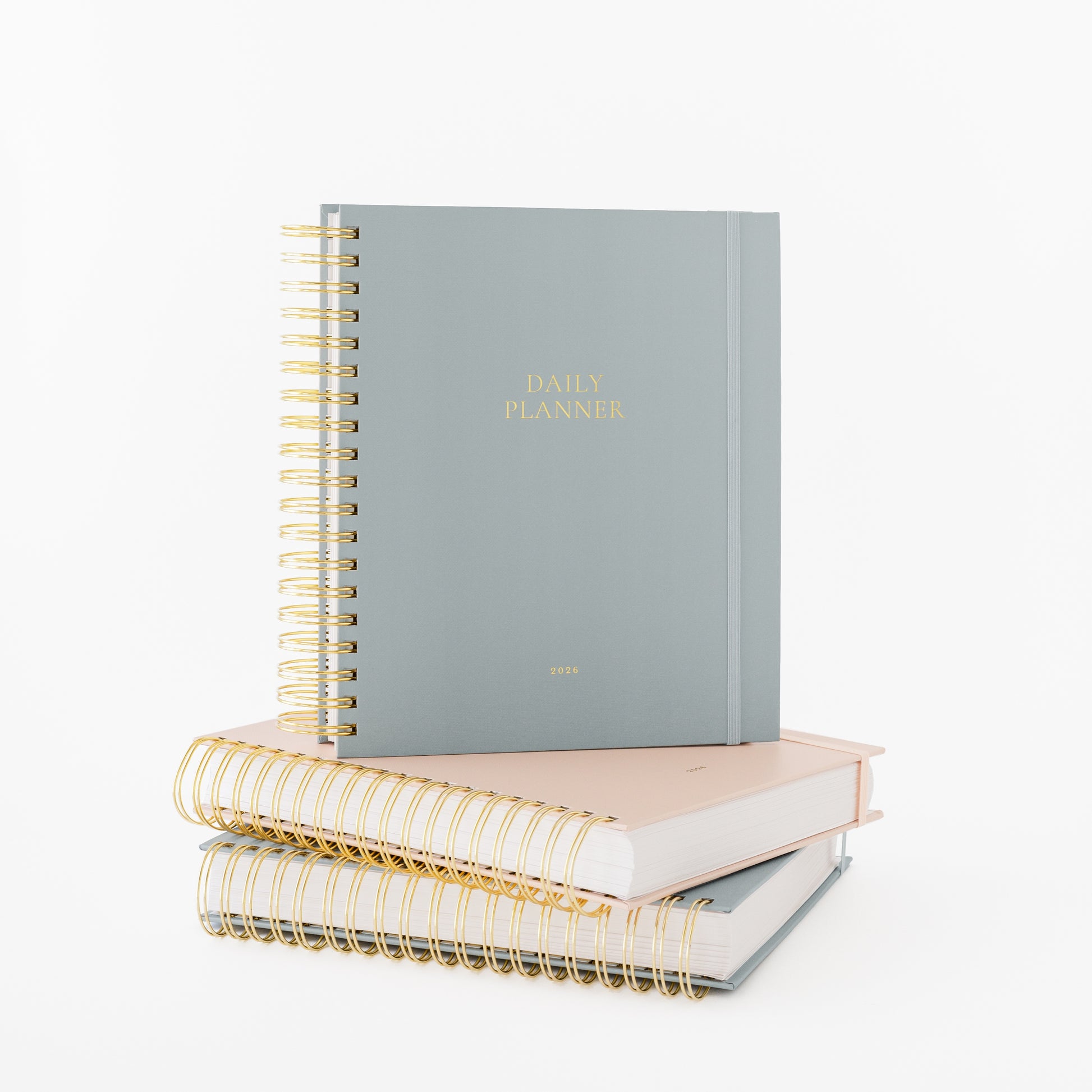 Stack of blue and pink spiral planners with gold wire binding