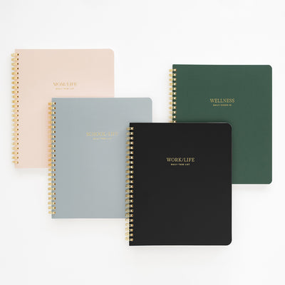 Set of four spiral-bound notebooks in different colors on a white background