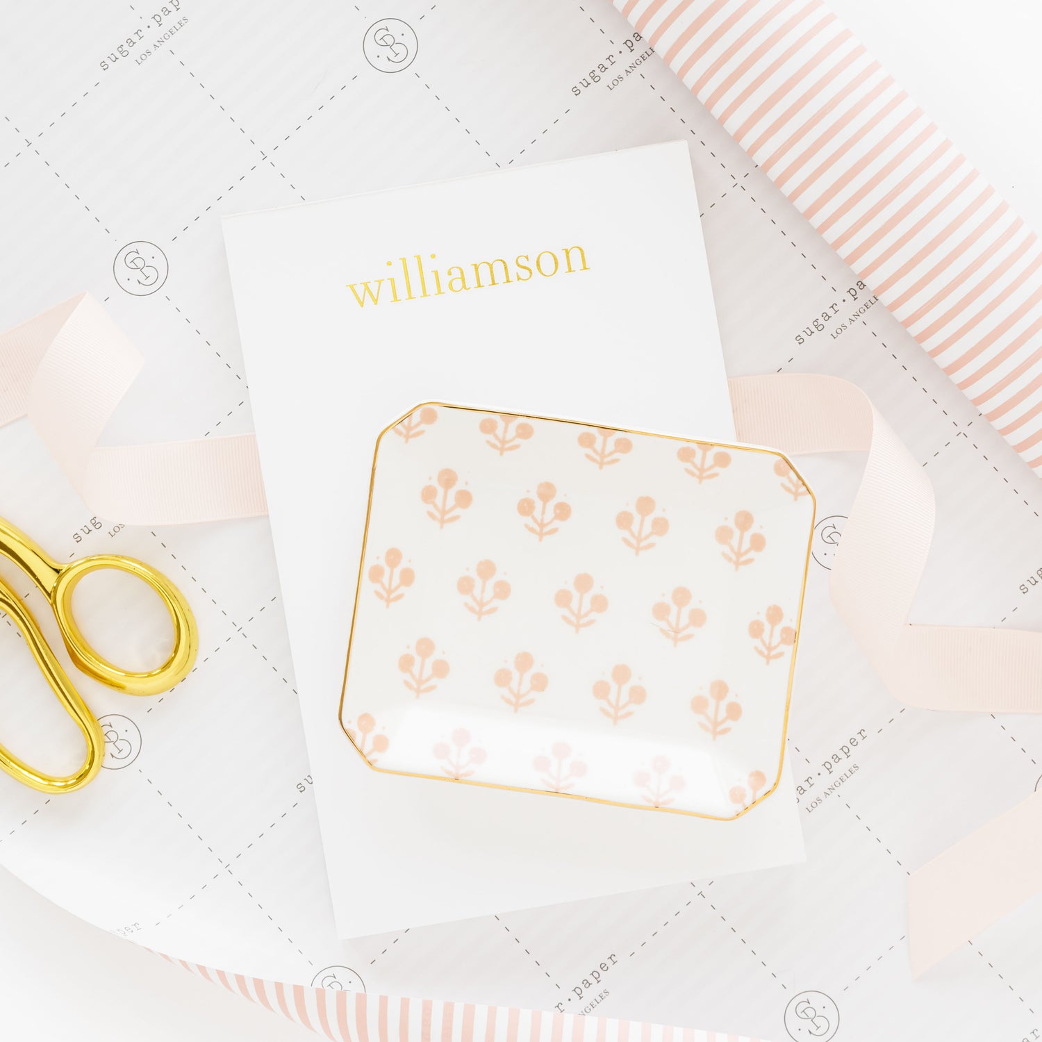 Decorative tray with floral pattern on a notepad with 'williamson' printed in gold.