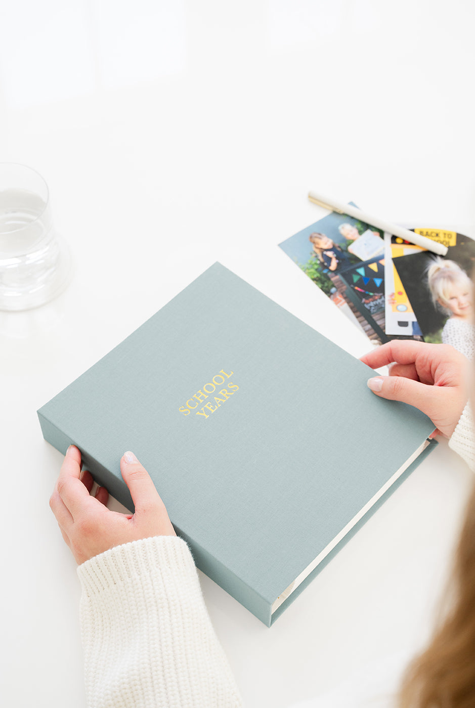 Person holding a light blue photo album with 'School Years' text on a white surface.