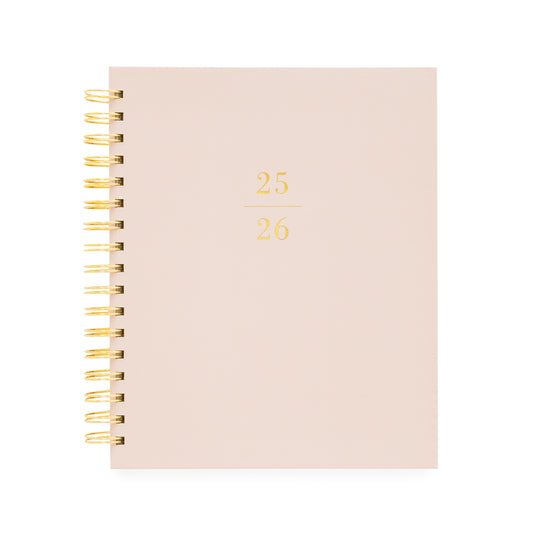 Dusty rose signature spiral planner with 25/26 on the cover in gold foil and a gold spiral binding