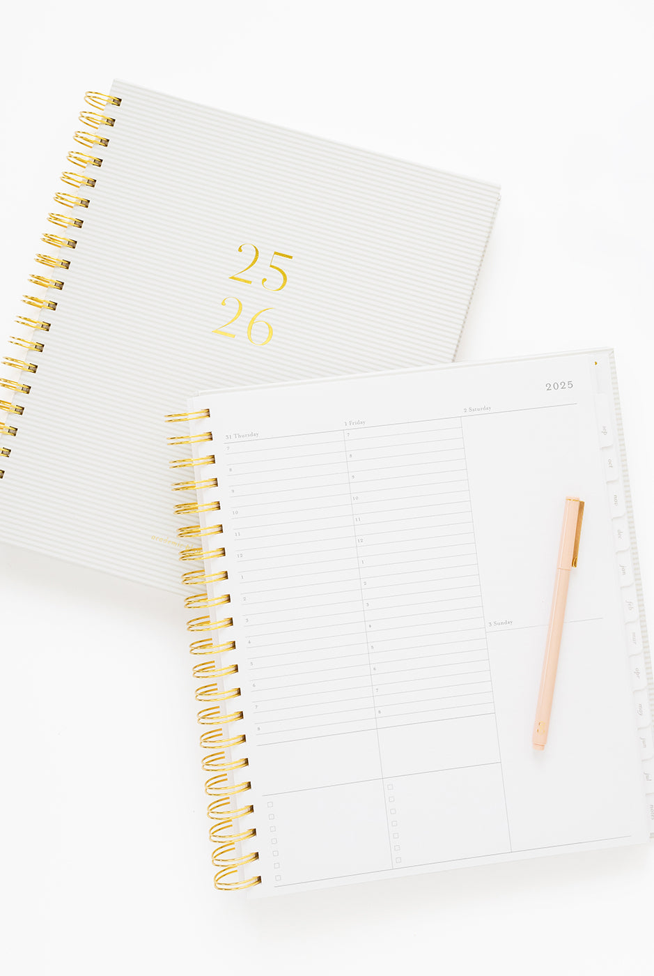 Two white planners with gold spiral binding on a white background