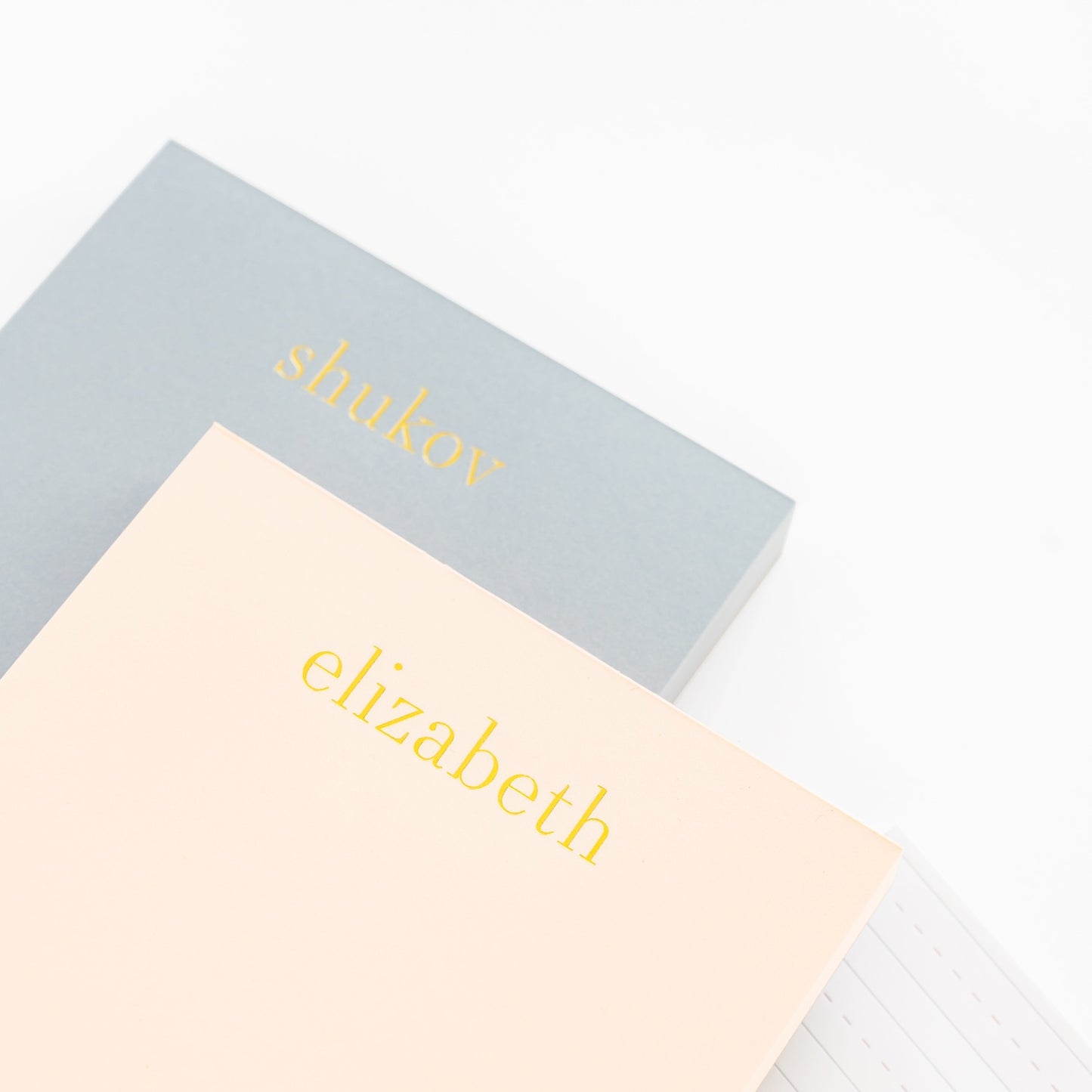 Stack of pink and blue custom notepads with gold foil names