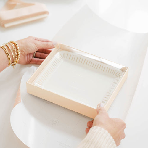 Woman wrapping ceramic tray with wrapping paper