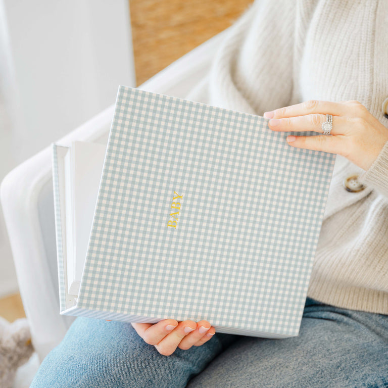 woman holding blue gingham baby book