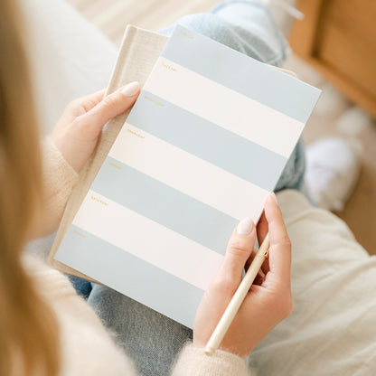 Blue and white striped weekly notepad in hand