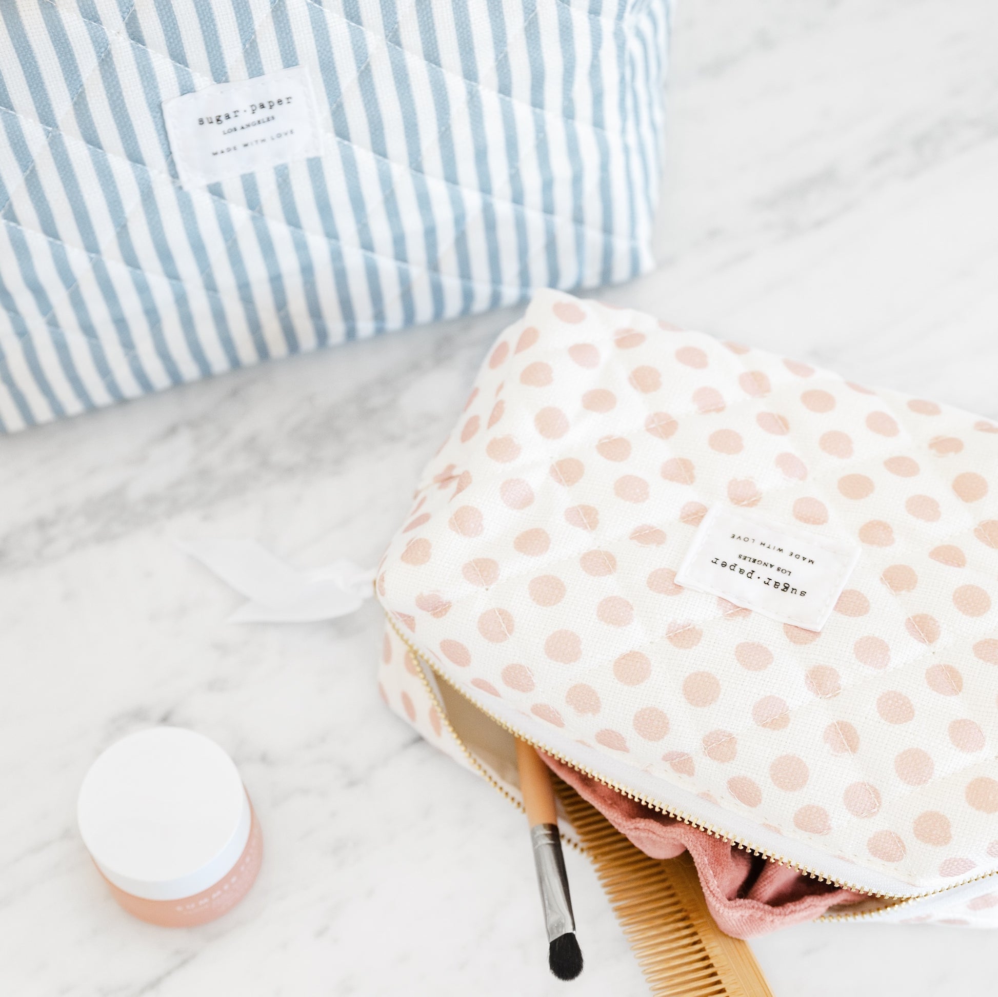 Rose dot and blue stripe cosmetic pouch on bathroom counter with makeup