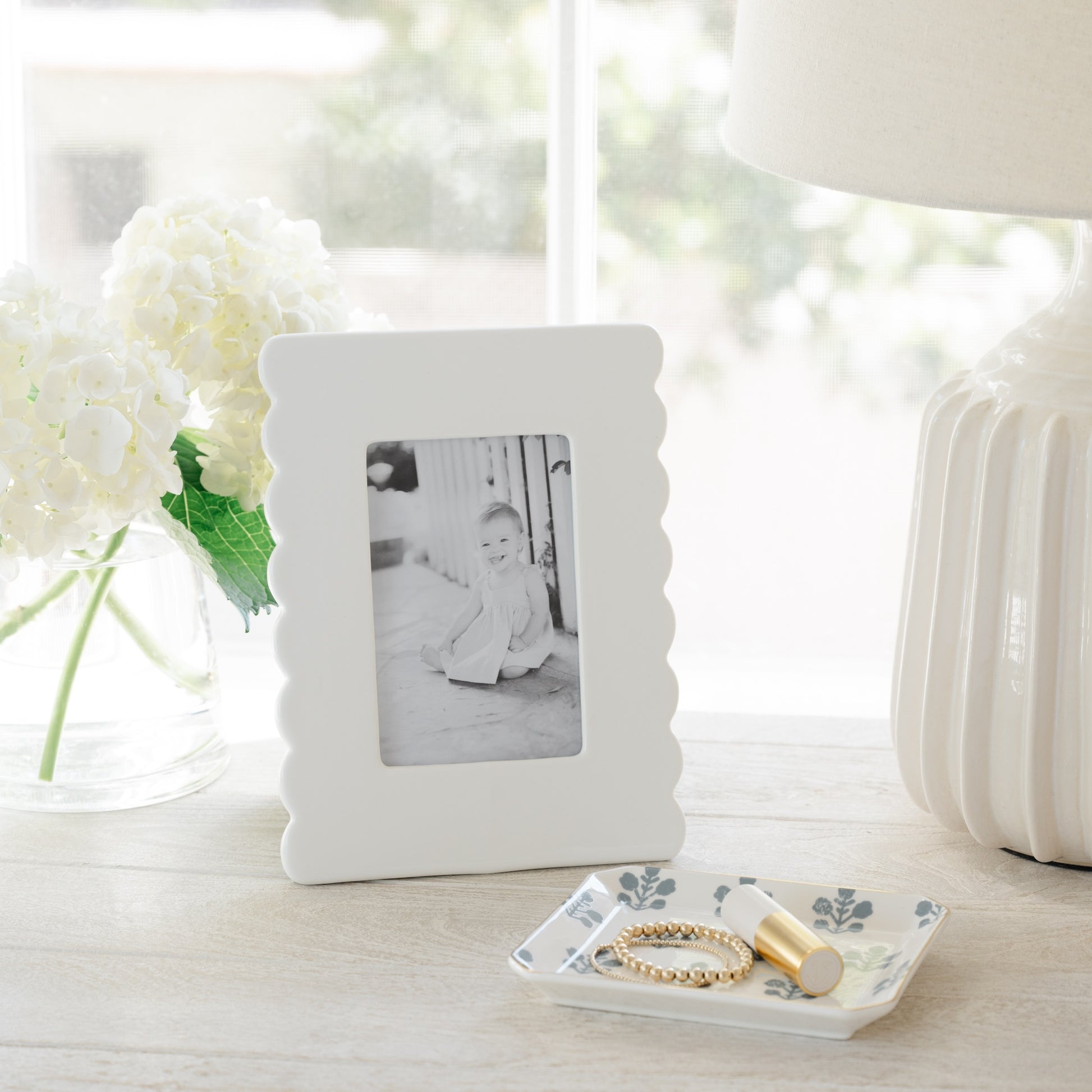 Dusty blue floral trinket tray on nightstand with white ceramic scallop frame