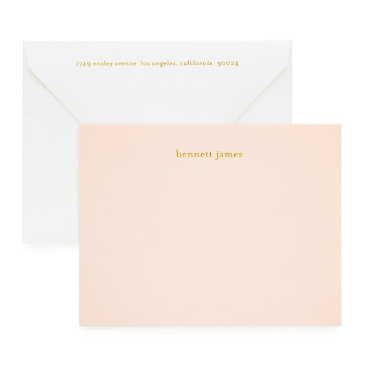 Pale pink custom stationery printed with gold foil paired with a white envelope