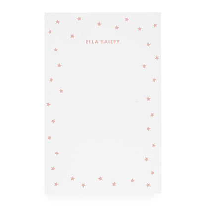 White notepad with scattered star bordered and 'ella bailey' text in rose ink
