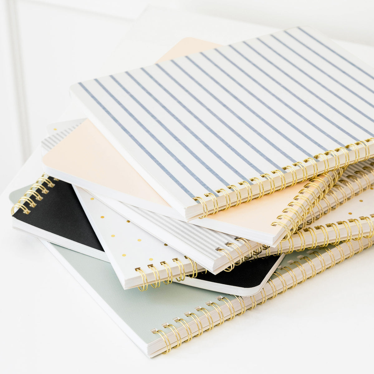 stack of different spiral notebooks in various patterns and colors