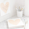 heart deskpad on a desk with assorted pens and note