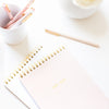 Spiral notebooks stacked with pens on desk
