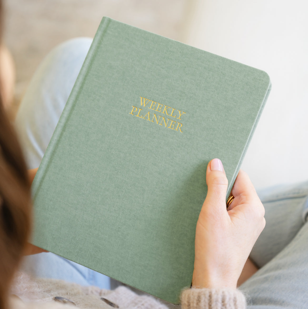 Sage green weekly planner in hands